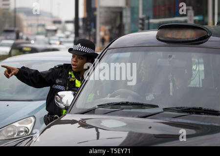 Polizisten direkten Verkehr als Taxis engagieren sich in einem "go slow" Protest auf dem Holloway Circus Kreisverkehr im Zentrum von Birmingham als Fahrer Protest über die Stadträte Pläne für eine neue saubere Luft Zone in Birmingham. Stockfoto