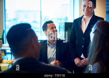 Kellnerin, die von Geschäftsleuten an der Bar Stockfoto