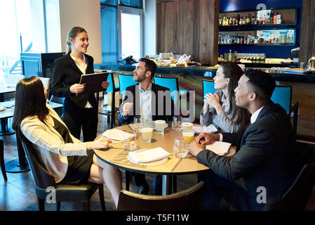 Kellnerin die Bestellungen von Geschäftsleuten in bar Stockfoto