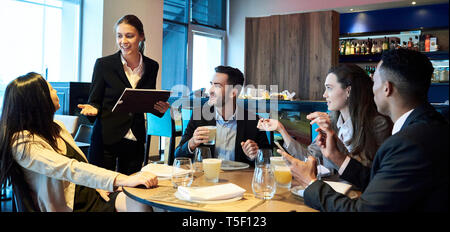 Kellnerin die Bestellungen von Geschäftsleuten in bar Stockfoto
