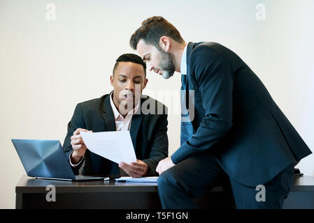 Unternehmer diskutieren Dokument am Schreibtisch im Büro Stockfoto