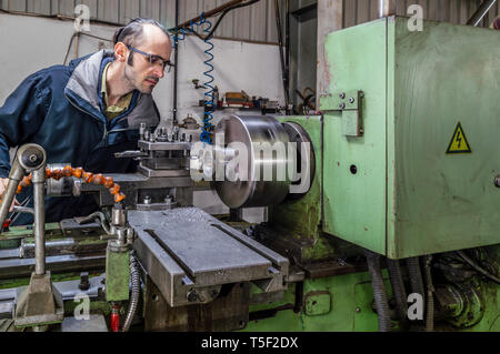 Kaukasische Ingenieur beobachten die Kopfplatte Drehmaschine Maschinen in einer Fabrik. Stockfoto