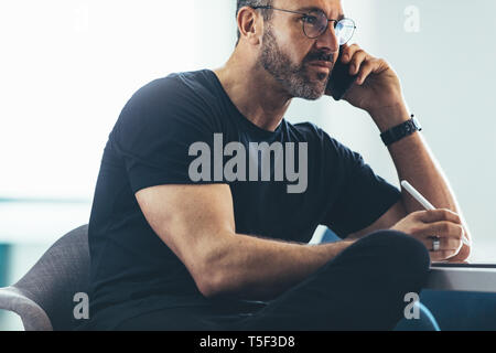 Reifen Geschäftsmann im Büro sitzen und Gespräch am Handy. Kaukasische Mann telefonieren. Stockfoto
