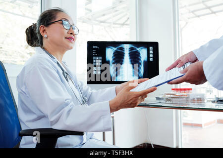 Ärztin unter ärztlicher Bericht Stockfoto