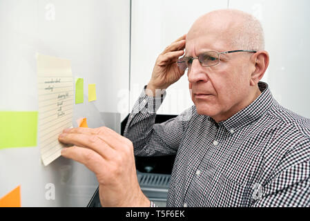 Ältere Mann an Noten suchen. Forgetful Senior mit Demenz, Memory Problem, Gesundheit Konzept Stockfoto