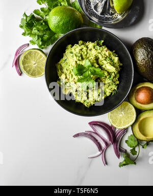 In der Nähe der Schüssel mit Guacamole und es Zutaten auf einem weißen Zähler. Stockfoto