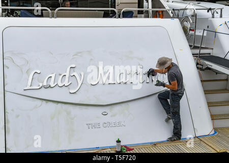 CANNES, Frankreich - April 2019: Person, die polnische, die auf dem Typenschild eines Superyacht im Hafen von Cannes. Stockfoto