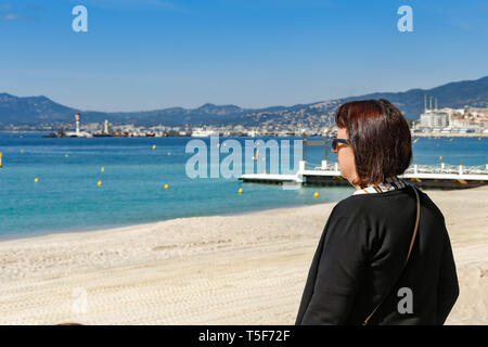 CANNES, Frankreich - April 2019: Person, die auf der Promenade in Cannes an der Côte d'Azur mit Blick auf die Bucht. Stockfoto