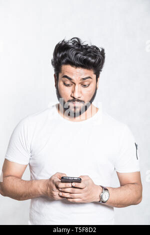 Jungen gutaussehenden Mann plaudern auf Handy. Stockfoto