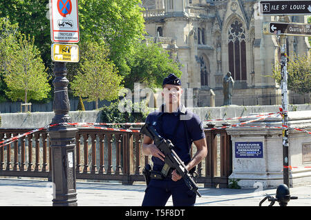 PARIS, FRANKREICH - 19. APRIL 2019: Bewaffnete Polizei (CRS) steht Wache mit halbautomatischen Waffen rund um die feuerbeschädigte Kathedrale Notre-Dame. Stockfoto