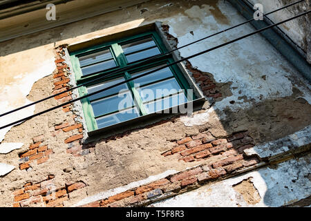 Eine alte Glasfenster mit umliegenden Reben an der Wand Stockfoto