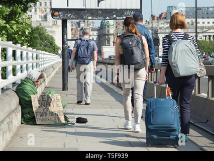 Ein scheinbar Obdachlosen mit einem handschriftlichen Karton Zeichen bitten um Essen auf der Waterloo Bridge in London mit Pendler und Reisende vorbei gehen. Stockfoto