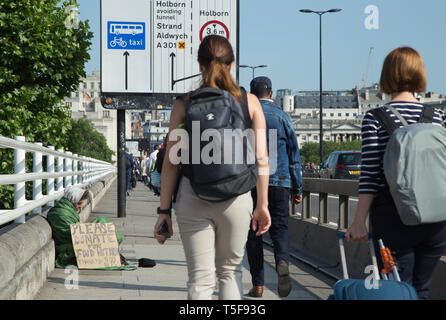 Ein scheinbar Obdachlosen mit einem handschriftlichen Karton Zeichen bitten um Essen auf der Waterloo Bridge in London mit Pendler und Reisende vorbei gehen. Stockfoto