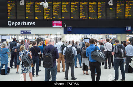 Reisende und Pendler, Warten, Zug an der belebten Bahnhofshalle am Waterloo Bahnhof in London Stockfoto