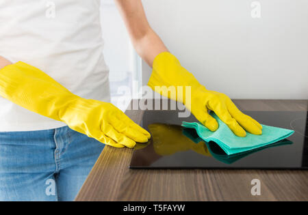 Eine junge Frau von einem professionellen Reinigungsfirma reinigt bis zu Hause. Ein Mann wäscht die Küche in gelb Handschuhe mit Reinigungsmittel Material. Stockfoto