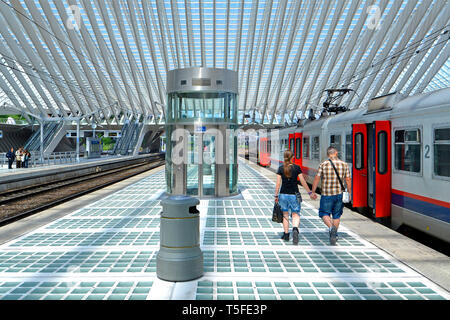 Rückansicht des jungen Mann & Frau Paar Hände halten entlang langer Bahnsteig in Lüttich Belgien modernes Bahnhofsgebäude Sommer Tag EU Stockfoto