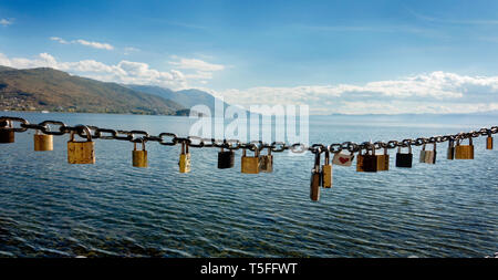 Vorhängeschlösser hängen an einer Kette mit einer Aussicht auf den See und die Berge Stockfoto