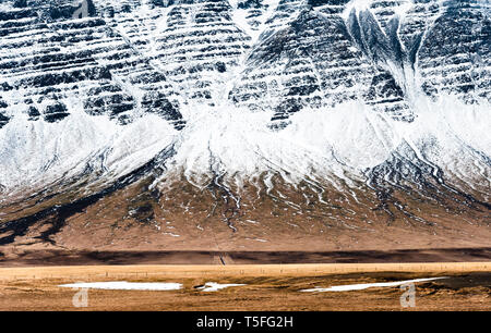 SW-Island Ende März am Ende des Winters. Die schneebedeckten Berge, die sich steil über Weideland steigende Stockfoto