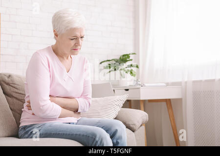 Traurige ältere Frau, ihren Bauch halten, leiden unter Bauchschmerzen Stockfoto