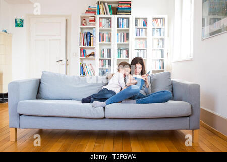 Schwestern sitzen auf der Couch, Buch lesen Stockfoto