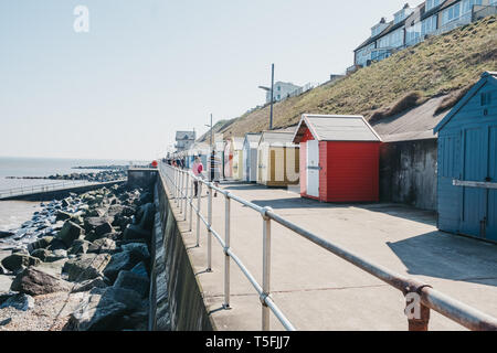 Sheringham, Großbritannien - 21 April, 2019: Menschen zu Fuß von bunten Badekabinen am Meer in Sheringham an einem sonnigen Tag. Sheringham ist eine englische Stadt am Meer Stockfoto