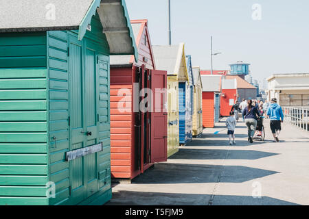 Sheringham, Großbritannien - 21 April, 2019: bunte Badehäuschen am Meer in Sheringham an einem sonnigen Tag, Menschen zu Fuß auf den Hintergrund. Sheringham ist ein Engl Stockfoto