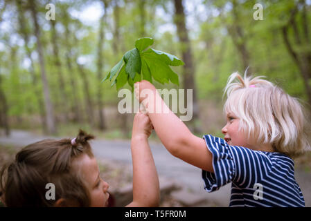 Zwei kleine Mädchen mit einem großen Blatt Stockfoto