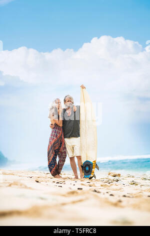 Senior hippie Paar stehend mit Surfbrett am Strand Stockfoto