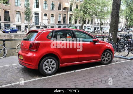 AMSTERDAM, NIEDERLANDE - 10 JULI 2017: rote Volkswagen Polo kleine Stadt Auto durch den Kanal in Amsterdam geparkt. Die Niederlande haben 528 registrierte Autos pro 1 Stockfoto