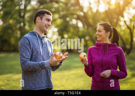 Junges Paar ist Essen Apple nach dem Training im Park. Stockfoto