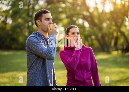 Junges Paar ist Essen Apple nach dem Training im Park. Stockfoto