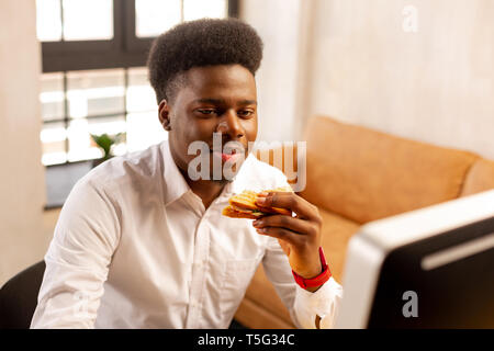 Angenehmer junger Mann mit einem leckeren Sandwich Stockfoto