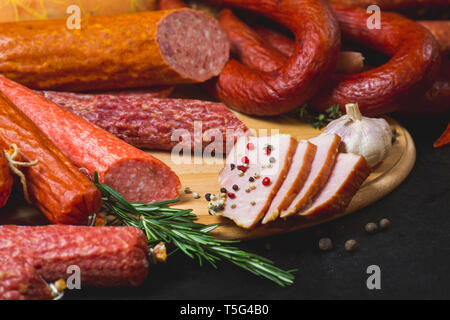 Verschiedene Arten von Wurst und Fleischerzeugnissen auf schwarzem Hintergrund Stockfoto