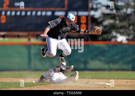 Zweiter Baseman springt, um einen gleitenden Basisläufer auf Sekunde zu vermeiden, der sicher mit einer gestohlenen Basis ankam, nachdem der Ball den Läufer getroffen hatte. USA. Stockfoto