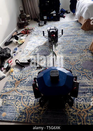 Eine Matterport-Kamera sitzt auf einem blau-goldenen Teppich in einem Raum, in dem verschiedene Geräte verstreut sind und wahrscheinlich einen 3D-Scan des Raumes aufnehmen. Stockfoto