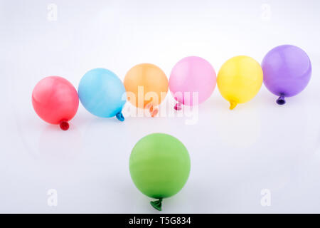 Bunte kleine Luftballons in Linie auf weißem Hintergrund Stockfoto