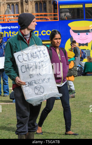 Westminster, London, UK, 24. April 2019. Eine Demonstrantin mit dem Klimawandel Plakat. Polizei versucht Aussterben Rebellion und Klimawandel Demonstranten camping haben hoch oben in einem Baum auf den Parliament Square, für mehrere Tage, um sie zu entfernen. Credit: Imageplotter/Alamy leben Nachrichten Stockfoto