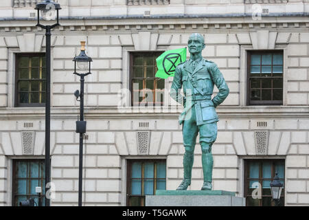 Westminster, London, UK, 24. April 2019. Ein Aussterben Rebellion Fahne hat, vorübergehend die Statue von Feldmarschall Jan Smuts in Parliament Square behoben. Polizei versucht Aussterben Rebellion und Klimawandel Demonstranten camping haben hoch oben in einem Baum auf den Parliament Square, für mehrere Tage, um sie zu entfernen. Credit: Imageplotter/Alamy leben Nachrichten Stockfoto