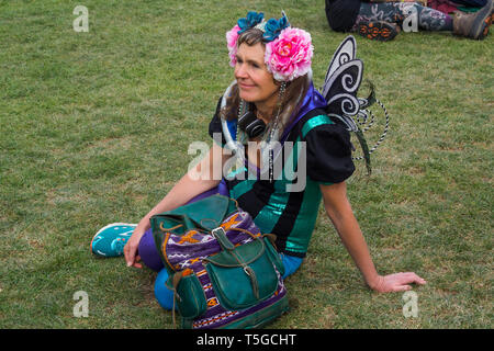 London, Großbritannien. 24. April 2019. Eine Frau mit Blumen im Haar und fairy Wings sitzt auf dem Gras wie Aussterben Rebellion eine Generalversammlung und Workshops im Parlament Platz halten, während einige Teilnahme an Masse lobby Treffen mit MPs waren. Einige Demonstranten wurden oben in den Bäumen und durch die Blätter versteckt. Wenn Berichte erreicht, die Polizei Anfang waren die Straßensperren im Marble Arch eine Gruppe hinter einer Samba Band zu löschen und begann bis März die Demonstranten dort zu unterstützen. Peter Marshall / alamy Leben Nachrichten Stockfoto
