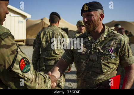 Camp Leatherneck, Helmand, Afghanistan. 25 Feb, 2012. British Royal Navy Haftbefehl Offier Stephen Morgan gratuliert von einem britischen Servicemember nach Erhalt der Britischen Meritorious Service Medal (MSM) in Camp Leatherneck, Provinz Helmand, Afghanistan, Jan. 26, 2012. Morgan erhielt die britische Meritorious Service Medal als Altersvorsorge Medaille nach 32 Jahren Service. In Afghanistan, er war ein Vertrag als Offizier für die NATO Training Mission in Afghanistan regionale Unterstützung Befehl Südwesten. Morgan in der Royal Navy, die Soldaten im Alter von 16 Jahren und im Falkland-krieg serviert an Bord der zerstören Stockfoto