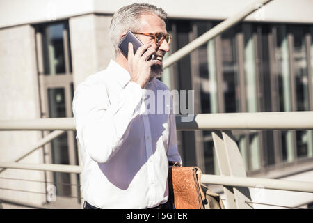 Gerne reife Geschäftsmann mit Mobiltelefon in der Stadt Stockfoto