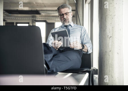 Reifen Geschäftsmann sitzen auf Stuhl mit Tablet Stockfoto