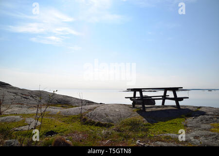 Leere Picknick Tisch und Bank auf den Klippen in den schwedischen Schären an einem schönen Morgen Stockfoto