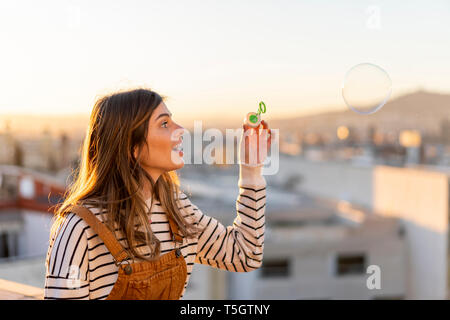 Junge Frau beobachten große Seifenblase erstaunt Stockfoto