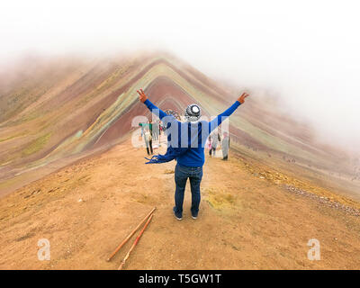 Eine junge männliche Touristen genießen den Blick auf die unglaubliche Rainbow Bergen außerhalb von Cusco, Peru. Die Beträge sind in einer Vielzahl von Farben aus der mineralischen Ablagerungen im Boden. Stockfoto