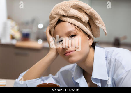 Portrait von lächelnden jungen Frau mit Haar in ein Handtuch gewickelt in der Küche Stockfoto