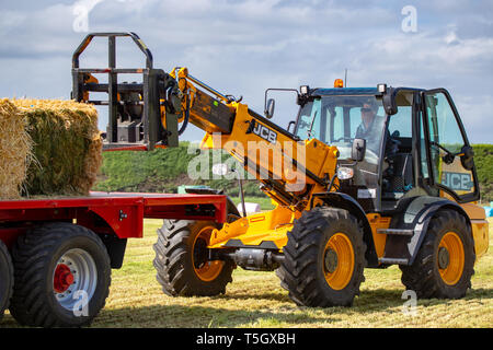 Kirwee, Canterbury, Neuseeland, 27. März 2019: der Landwirt wird veranschaulicht, wie die JCB Teleskoplader funktioniert so gut stapeln haybales auf der Südinsel Agri Stockfoto