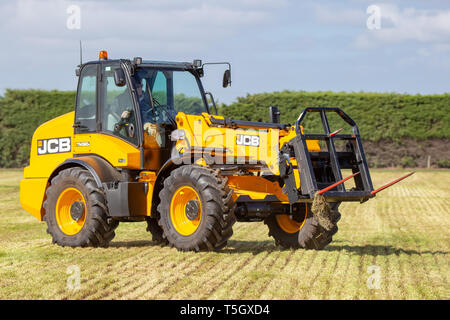 Kirwee, Canterbury, Neuseeland, 27. März 2019: der Landwirt zeigt eine JCB Teleskoplader bei der Arbeit stapeln haybales, Südinsel landwirtschaftliches Feld Tag Stockfoto