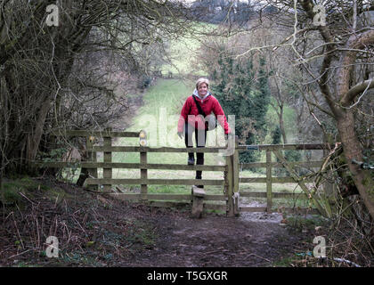 UK, Gloucester, Chipping Sodbury, Cotswold Way, Frau auf einer Wanderung Kreuzung Weidezaun Stockfoto