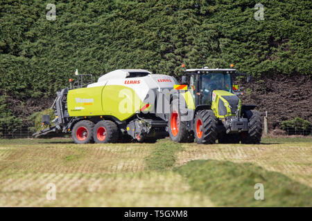 Kirwee, Canterbury, Neuseeland, 27. März 2019: ein Claas Presse und Traktor am Arbeitsplatz die Heuballen auf der Südinsel landwirtschaftliches Feld Tage Veranstaltung Stockfoto